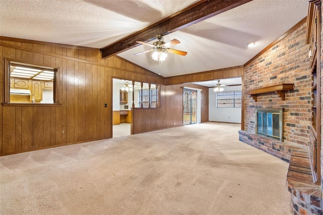 unfurnished living room featuring wood walls, lofted ceiling with beams, a textured ceiling, light colored carpet, and a fireplace