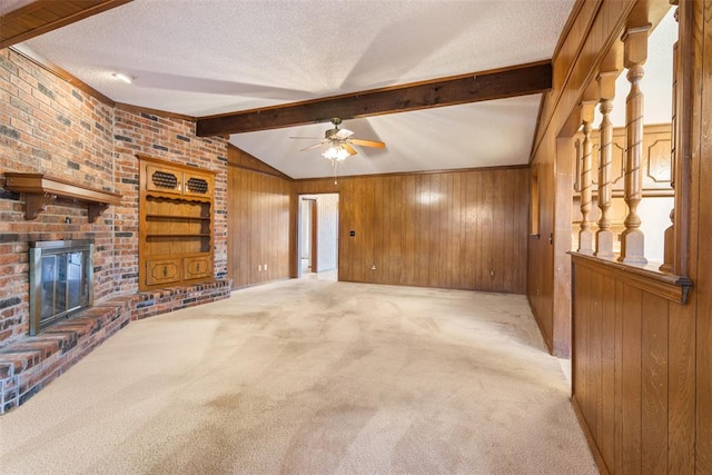 unfurnished living room featuring a brick fireplace, wooden walls, vaulted ceiling with beams, and a textured ceiling