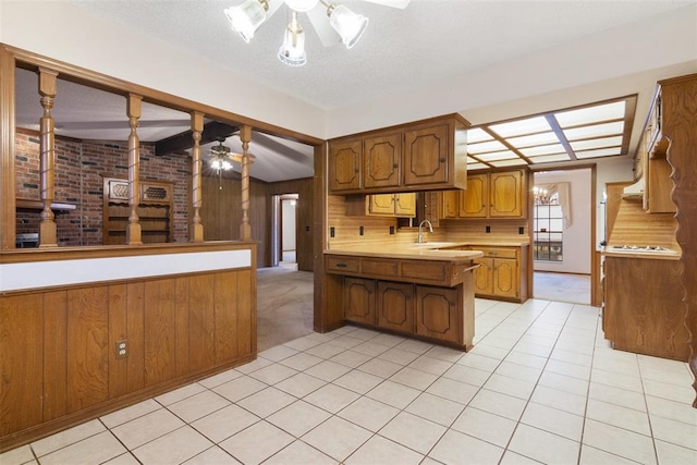 kitchen with sink, a textured ceiling, wooden walls, kitchen peninsula, and ceiling fan