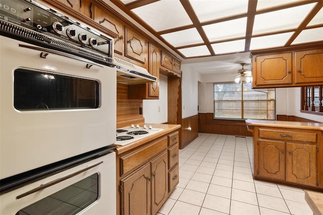 kitchen with ceiling fan, light tile patterned floors, white appliances, and wood walls