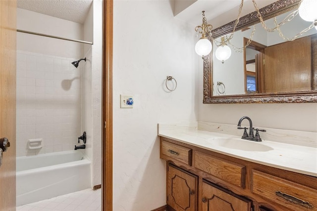 bathroom with tile patterned floors, tiled shower / bath, vanity, and a textured ceiling