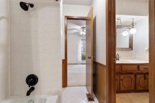 bathroom with tiled shower / bath combo, vanity, ceiling fan, and a textured ceiling