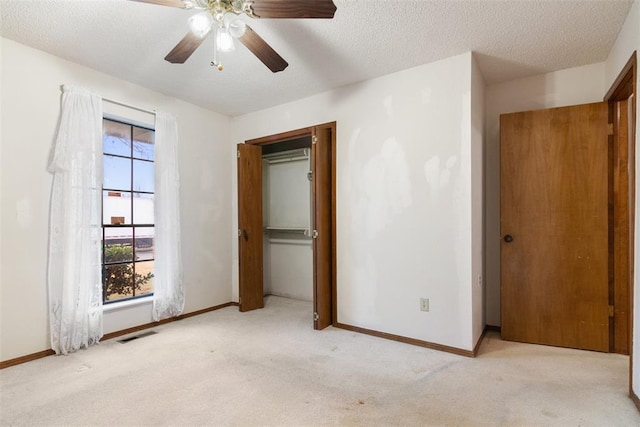 unfurnished bedroom with ceiling fan, light carpet, and a textured ceiling