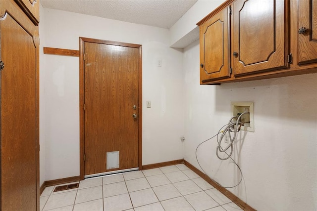 washroom featuring cabinets, washer hookup, a textured ceiling, and light tile patterned floors