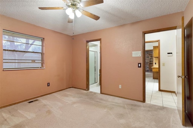 unfurnished bedroom with connected bathroom, light colored carpet, a textured ceiling, and ceiling fan