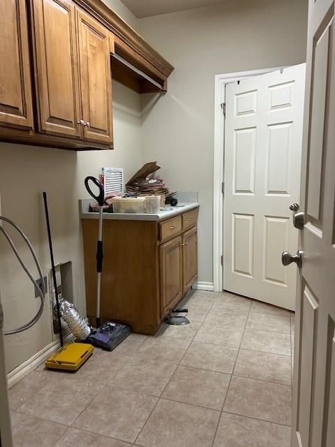 clothes washing area featuring light tile patterned floors and cabinets