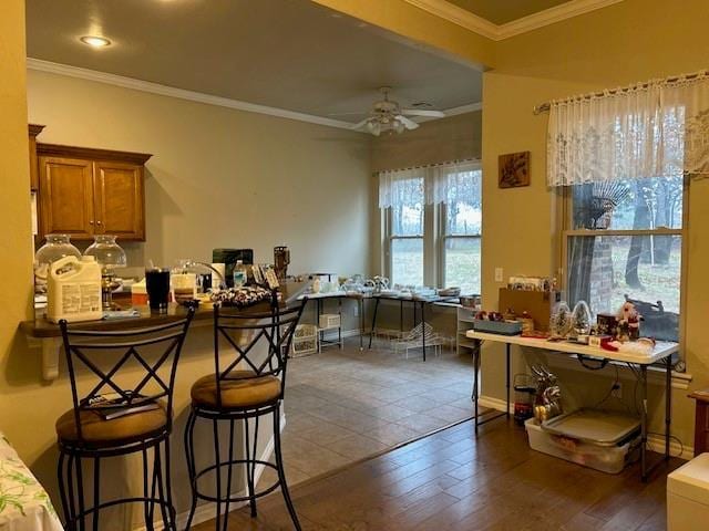 kitchen with a kitchen breakfast bar, crown molding, dark hardwood / wood-style flooring, and ceiling fan