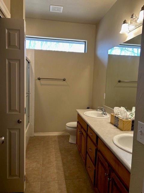 full bathroom featuring vanity, combined bath / shower with glass door, and toilet