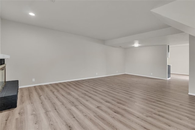 unfurnished living room with a brick fireplace and light hardwood / wood-style flooring