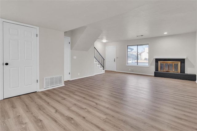 unfurnished living room with a brick fireplace and light hardwood / wood-style flooring