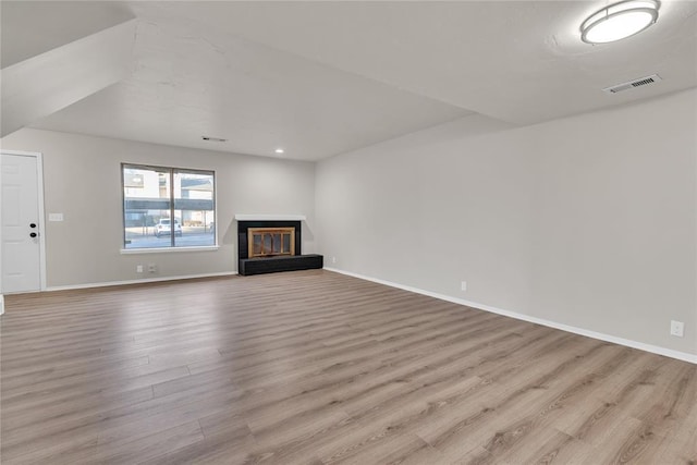 unfurnished living room featuring light hardwood / wood-style flooring and a multi sided fireplace