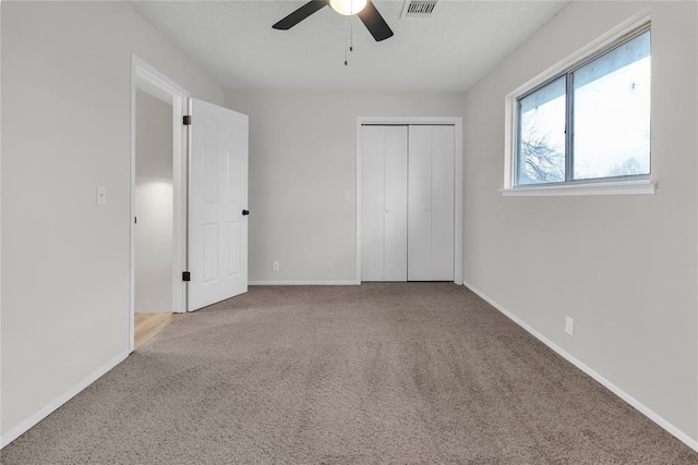 unfurnished bedroom featuring ceiling fan, light colored carpet, and a closet