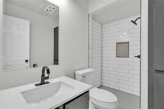 bathroom with vanity, toilet, and tiled shower