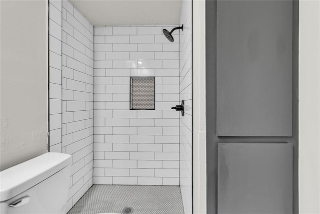 bathroom with a tile shower and toilet