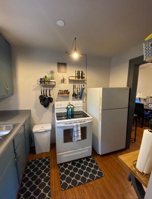 kitchen with hardwood / wood-style flooring, white appliances, and gray cabinetry