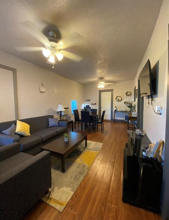 living room with hardwood / wood-style floors, a textured ceiling, and ceiling fan