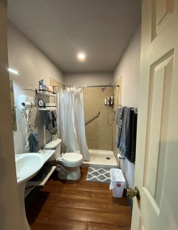 bathroom with sink, hardwood / wood-style flooring, curtained shower, and toilet