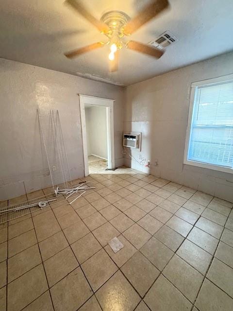 spare room featuring a wall mounted air conditioner, light tile patterned floors, and ceiling fan