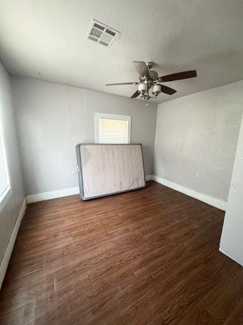 empty room featuring a wealth of natural light, dark wood-type flooring, and a textured ceiling