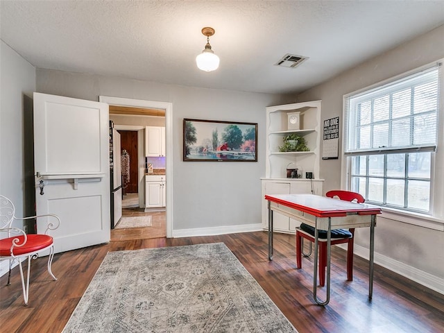 dining room featuring a textured ceiling and dark hardwood / wood-style flooring