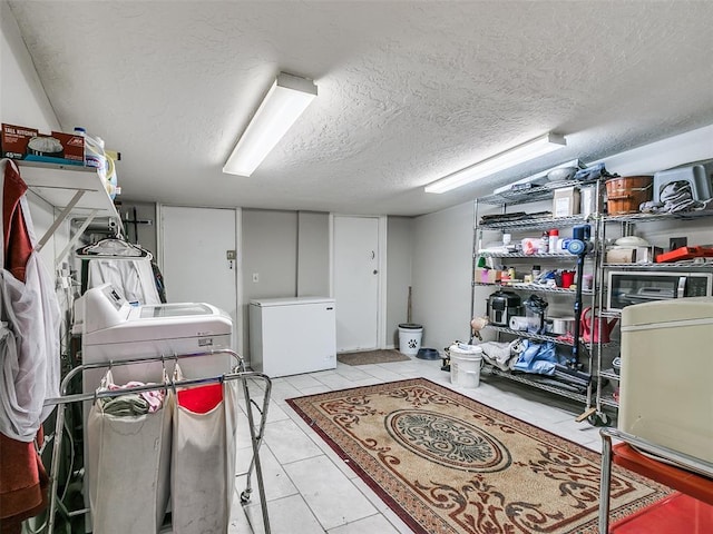 washroom with separate washer and dryer, light tile patterned floors, and a textured ceiling