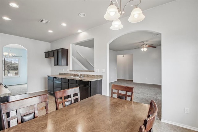 carpeted dining area with sink and ceiling fan with notable chandelier