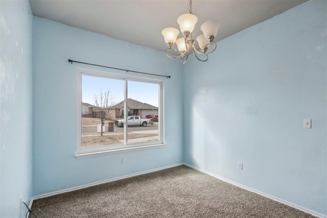 carpeted spare room featuring a chandelier