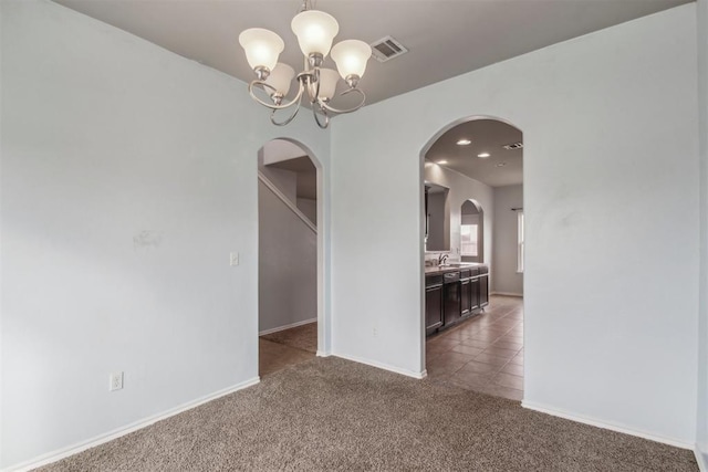 carpeted spare room featuring sink and a notable chandelier