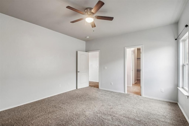 unfurnished bedroom with ceiling fan, a spacious closet, carpet floors, and a closet