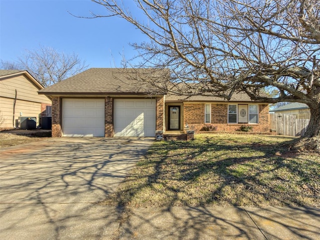 ranch-style home with cooling unit, a garage, and a front yard