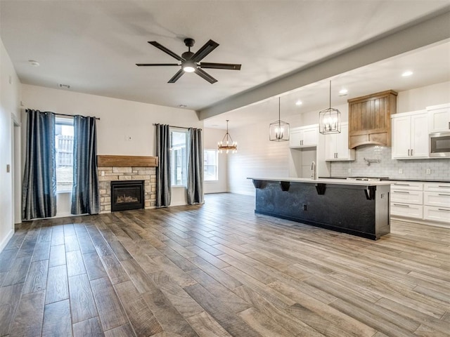 kitchen featuring a breakfast bar, decorative light fixtures, white cabinets, decorative backsplash, and a kitchen island with sink