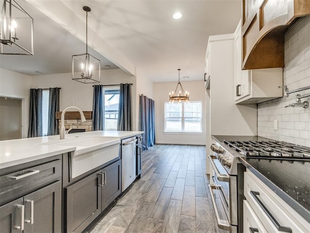 kitchen featuring white cabinetry, stainless steel appliances, decorative light fixtures, and a notable chandelier