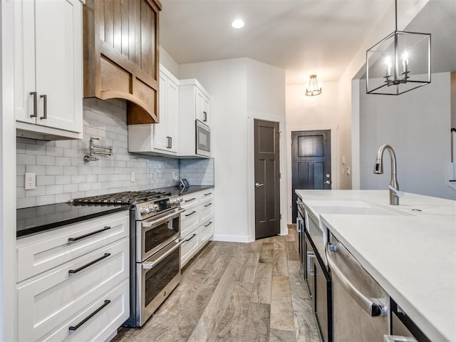 kitchen featuring sink, tasteful backsplash, hanging light fixtures, stainless steel appliances, and white cabinets