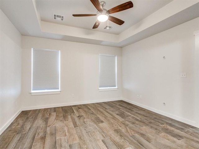 empty room featuring a tray ceiling, ceiling fan, and hardwood / wood-style flooring