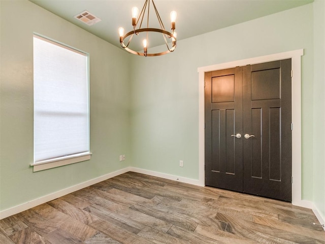 empty room featuring hardwood / wood-style floors and a notable chandelier