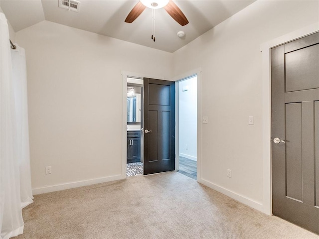 unfurnished bedroom featuring ceiling fan, light colored carpet, lofted ceiling, and ensuite bath