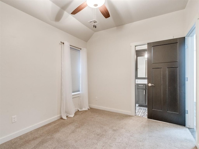 unfurnished bedroom with ceiling fan, lofted ceiling, connected bathroom, and light carpet