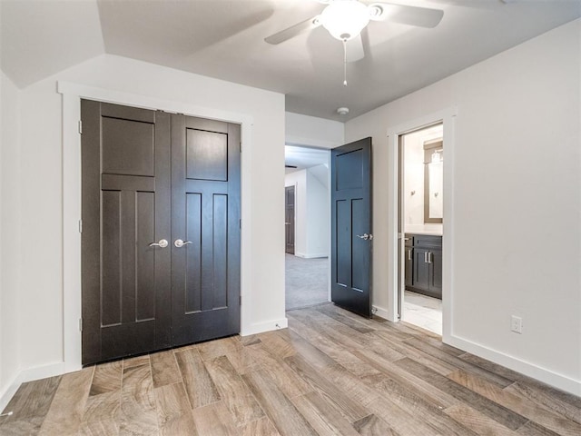 unfurnished bedroom featuring ensuite bathroom, ceiling fan, and light wood-type flooring