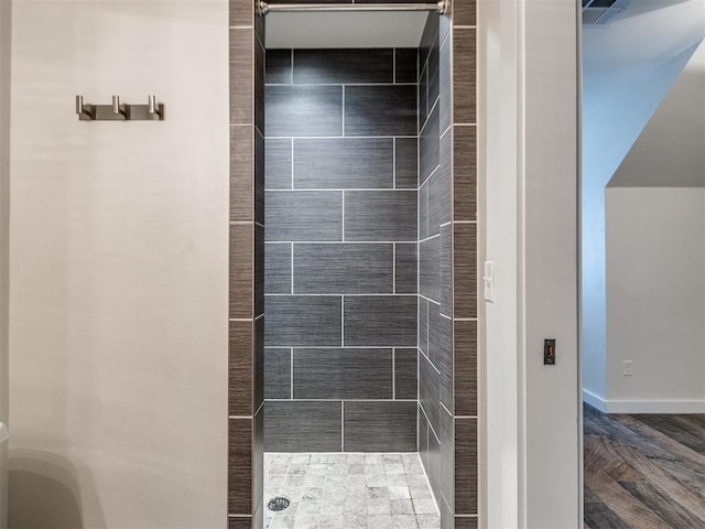 bathroom featuring a tile shower and wood-type flooring