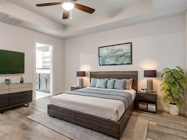 8909 NW 129th St, Oklahoma City, OK 73142 - bedroom with wood finished floors, a tray ceiling, connected bathroom, baseboards, and a ceiling fan