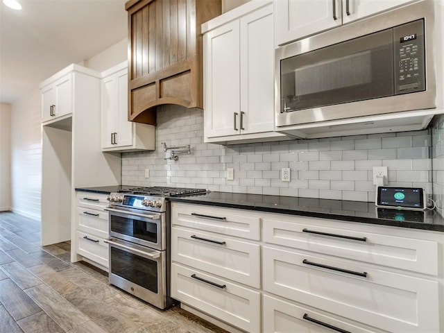 8909 NW 129th St, Oklahoma City, OK 73142 - kitchen featuring appliances with stainless steel finishes, white cabinets, decorative backsplash, and dark stone counters