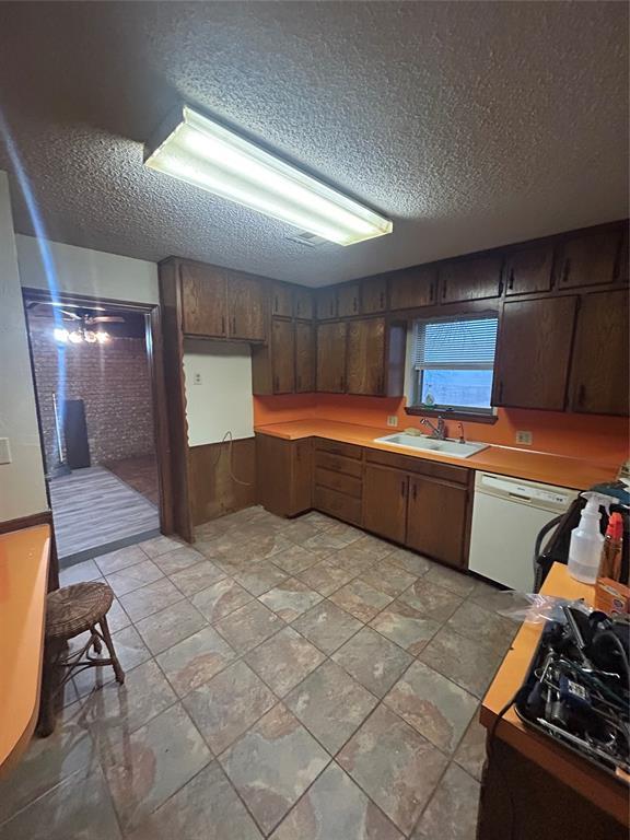 kitchen featuring white dishwasher, sink, dark brown cabinets, and a textured ceiling