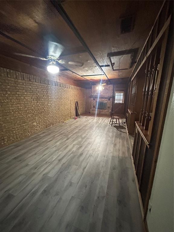 basement with brick wall and wood-type flooring