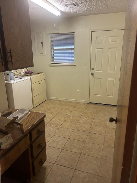 washroom with light tile patterned flooring, cabinets, washing machine and clothes dryer, electric panel, and a textured ceiling