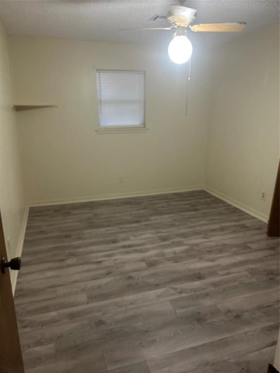 empty room with ceiling fan, dark hardwood / wood-style flooring, and a textured ceiling