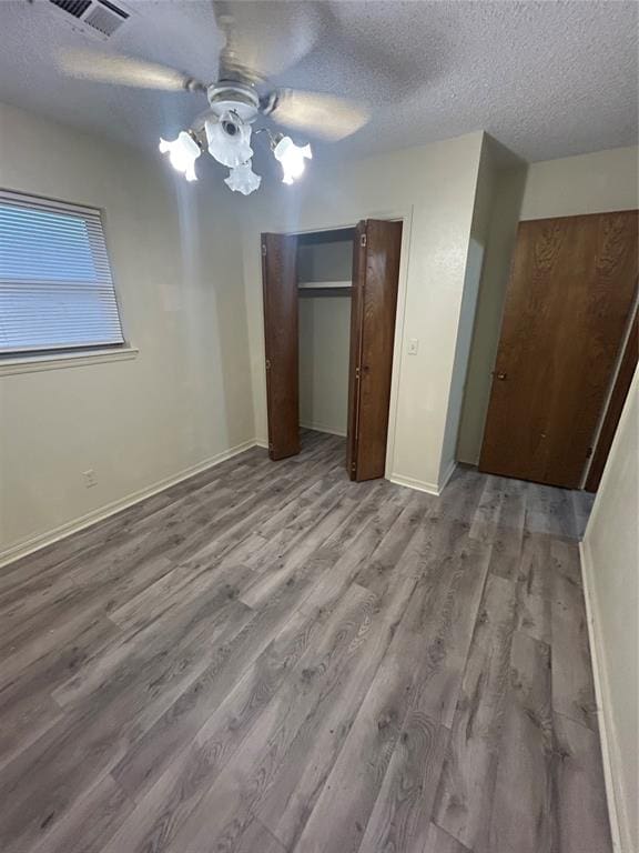 unfurnished bedroom with ceiling fan, a textured ceiling, and light wood-type flooring