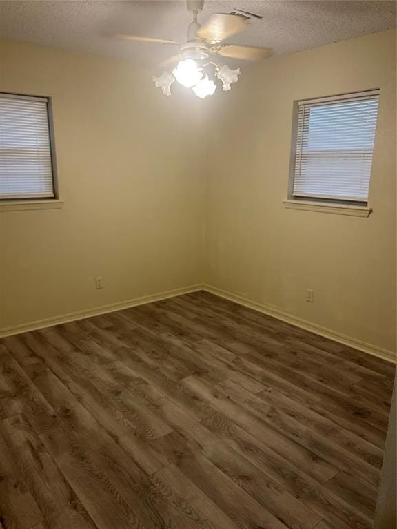 empty room with ceiling fan, dark hardwood / wood-style floors, and a textured ceiling