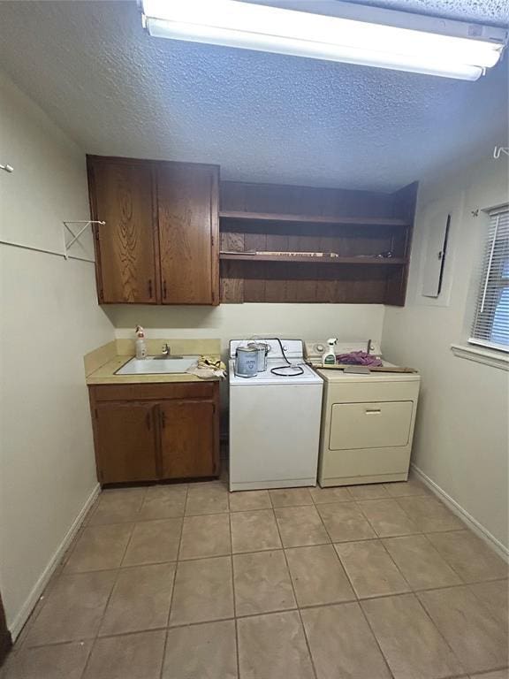 clothes washing area with light tile patterned flooring, washer / clothes dryer, and a textured ceiling