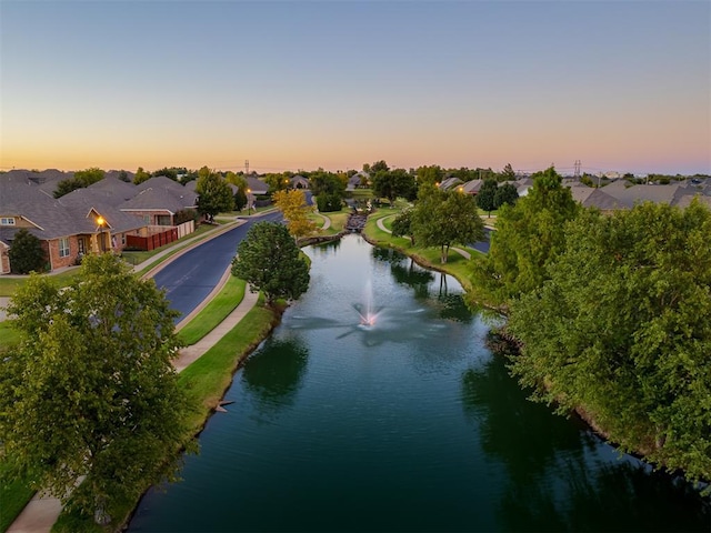 aerial view at dusk featuring a water view