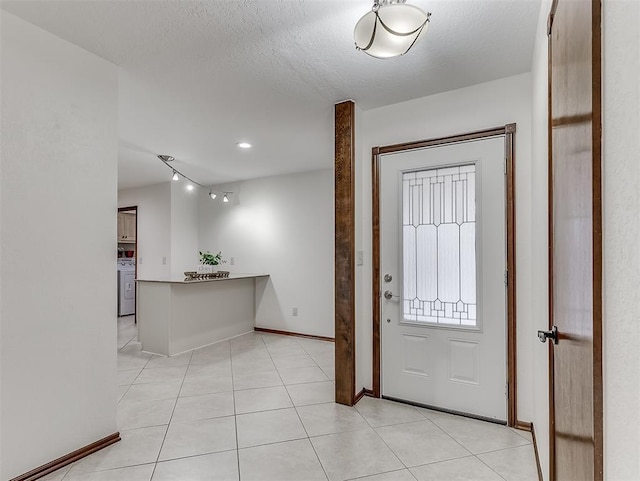 entryway featuring washer / clothes dryer, light tile patterned floors, and a textured ceiling